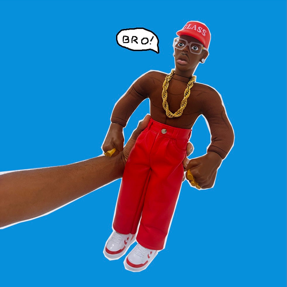A collectible doll of a Tyler, The Creator wearing a red cap with 'GLASS' in white, a chunky gold chain, red pants, and white sneakers, isolated on a white background.
